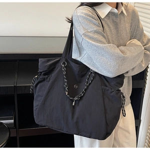 Dettaglio della borsa tote in tela nera con corda intrecciata e logo in metallo