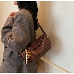 Detail of dark brown woven shoulder bag with vintage beaded charms and retro texture