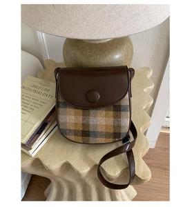Detail of vintage saddle bag with brown leather and plaid stitching on display