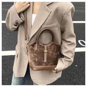 Détail du sac seau en velours marron et cuir avec boucle dorée et bandoulière