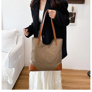 Detail of khaki fabric tote bag with brown leather handles and reinforced base corners