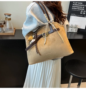 Detail of khaki suede tote bag with brown leather straps and baseball glove charm