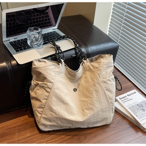 Dettaglio della borsa tote beige in tela con manici in corda su una panca in pelle nera
