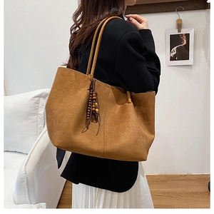 Brown suede tote bag with wooden bead tassel shown on model for daily commute styling