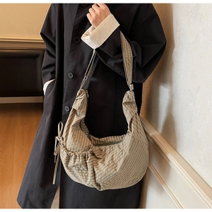 Detail of checkered canvas hobo bag showing pleated drawstring design and a wide shoulder strap