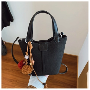Dettaglio borsa a secchiello in camoscio nero con logo COIH 2DN e ciondolo boho