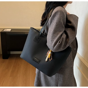 Détail du sac cabas noir avec anses en cuir brillant et breloques en perles colorées