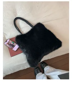 Detail of fluffy black faux fur tote bag with thick braided leather strap on bed