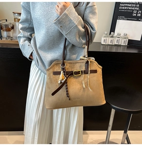 Detail view of large brown suede tote bag with leather straps and golden buckle