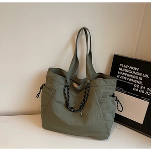 Dettaglio macro della borsa tote in nylon verde militare con nodo in corda e logo metallico