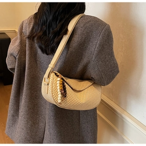Detail of beige woven dumpling bag with wooden bead tassel and synthetic leather strap