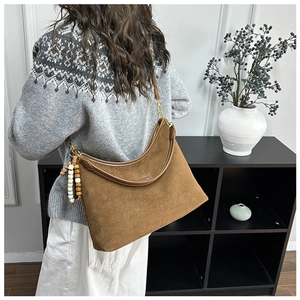 Detail einer großen braunen Wildleder-Hobo-Tasche mit Holzperlen-Anhänger und Ledergriff