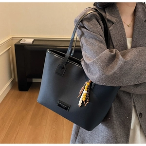 Détail du sac cabas vintage noir avec matière texturée et accessoire de charme en perles