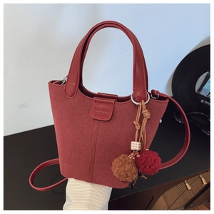 Dettaglio della borsa a secchiello in camoscio rosso con logo e nappa colorata