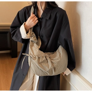 Detail of checkered canvas hobo bag with adjustable side drawstring and brown grid pattern
