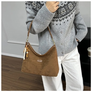 Details der braunen matten Leder-Schultertasche mit einem bunten Perlen-Fransenanhänger