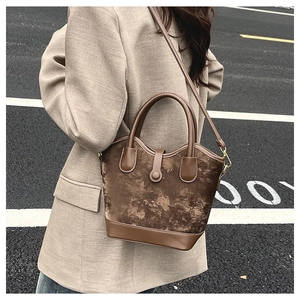 Détail d'un sac seau vintage marron en daim texturé marbre avec des lanières en cuir