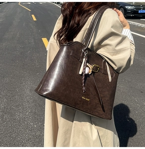 Close-up of large brown faux suede tote bag with vintage texture and baseball charms