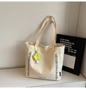 Detail of canvas tote bag with Viva La Vida text print and yellow flower charm