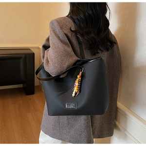Détail du sac cabas en similicuir noir avec texture litchi et pendentif en perles