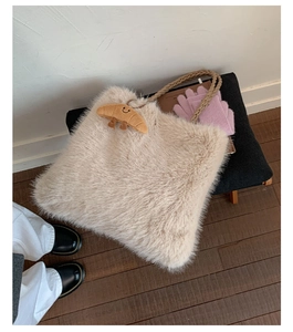 Detailed view of beige fluffy plush tote bag with brown woven rope handles and a small charm