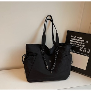 Dettaglio della borsa tote in nylon nero con nodo intrecciato e logo in metallo