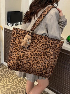 Fashionable leopard print velvet tote bag with bear charm shown on a female model