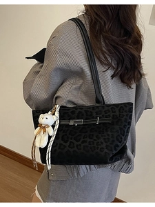 Large black leopard print tote bag with plush bear charm shown on model shoulder