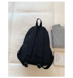 Detail eines schwarzen Nylon-Rucksacks mit verstellbaren Trägern und verstecktem Fach