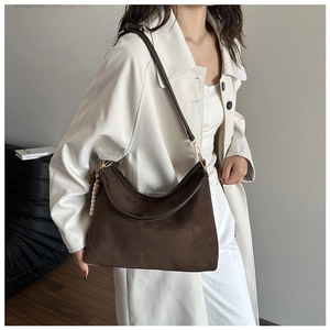 Detailaufnahme der braunen Wildleder-Hobo-Tasche mit Vintage-Perlenanhänger und Gold