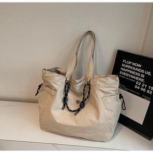 Dettaglio della borsa tote in tela bianco avorio con coulisse e tasca laterale su marmo