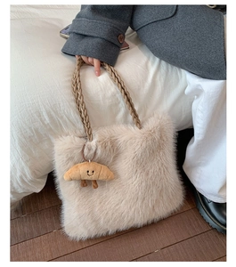 Detail of beige faux fur tote bag with brown braided handles and cute plush charm