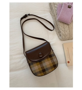 Retro plaid saddle bag close-up on cozy beige fabric with winter lifestyle props