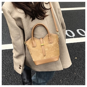 Détail du sac seau en daim kaki avec lanières en cuir et boucle métallique dorée
