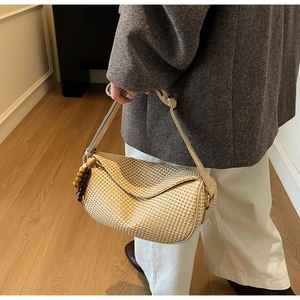 Detail of woven straw dumpling bag with wooden beads and adjustable leather strap