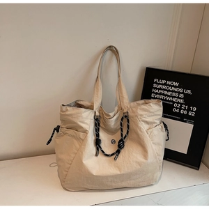 Dettaglio della borsa tote in nylon beige con coulisse a spirale e logo del marchio