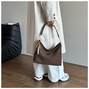 Detailansicht der dunkelbraunen Hobo-Tasche aus Wildleder mit dekorativem Perlenanhänger