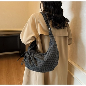 Detail of grey checkered crescent bag showing side drawstring bow and adjustable strap