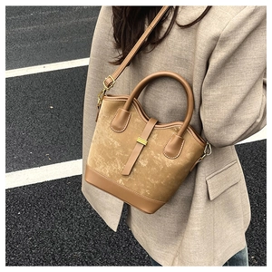 Détail d'un sac bandoulière marron en cuir bicolore avec des boucles dorées