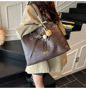 Detail view of large dark brown suede tote bag with decorative strap and buckle