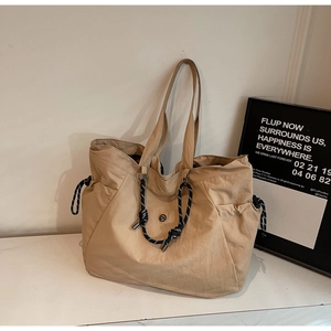 Dettaglio della borsa tote in tela kaki con manici intrecciati e chiusura magnetica