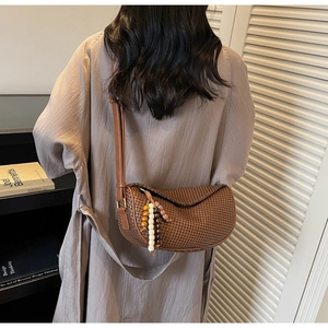 Detail of woven straw crossbody bag with decorative wooden beads and leather strap