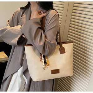 Détail du sac fourre-tout rétro en toile crème avec anses en cuir et charme perlé