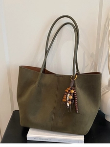 Minimalist olive green suede tote bag with vintage beaded tassel on white books