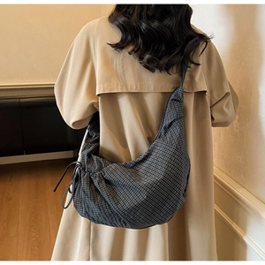 Detailed view of large checkered canvas crescent bag with drawstring detail on a model