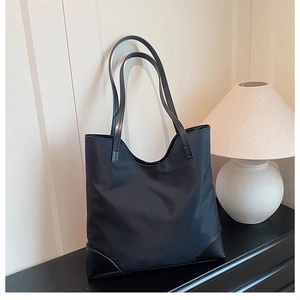 Close-up of black tote bag featuring nylon fabric and leather handle in a home setting