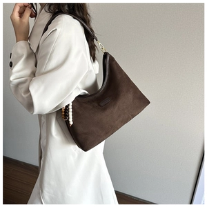 Close-up of brown suede hobo bag featuring golden hardware and decorative wooden beads