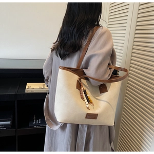 Gros plan sur le sac fourre-tout en toile beige avec bordure en cuir marron et bijou