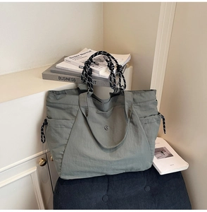 Dettaglio della borsa tote grigio-verde con manici in corda intrecciata e logo in metallo