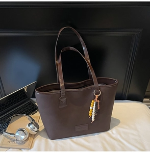 Détail du sac cabas marron foncé avec pompon en perles et décor d'ordinateur portable